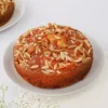 Plum and Almond Fruitcake with sliced plums and toasted almonds on top, served on a decorative plate.