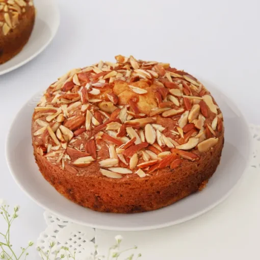 Plum and Almond Fruitcake with sliced plums and toasted almonds on top, served on a decorative plate.