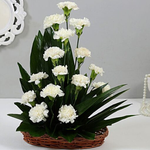 Pure Elegance Cane Basket – white carnations arranged in a natural cane basket with elegant greenery