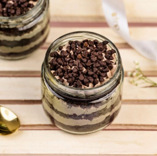 Set of six cream cake jars layered with sweet cream and chocolate chips in clear glass jars