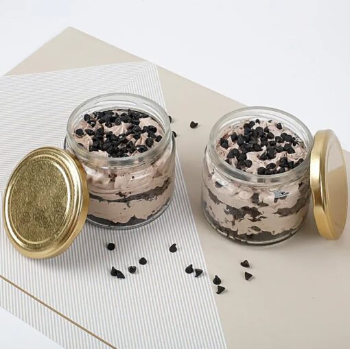 Two gourmet chocolate cake jars with layers of moist chocolate cake and creamy frosting in clear jars