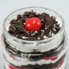 Two Black Forest cake jars with layers of chocolate sponge, whipped cream, cherries, and chocolate shavings in clear jars