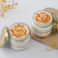 Layered dessert jar with golden cookie crumble, creamy filling, and cake, presented in a clear glass jar