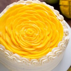 Fresh Mango Fruit Cake with moist mango-infused sponge, whipped cream frosting, and fresh mango slices on top.