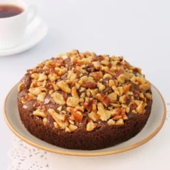 Date and Nut Fruitcake with chopped dates and mixed nuts on top, sliced on a rustic wooden board.