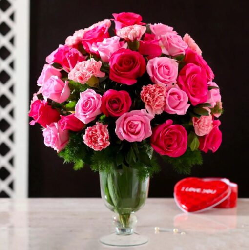 Elegant Roses Carnations Vase – fresh pink and red roses with carnations arranged in a clear glass vase.