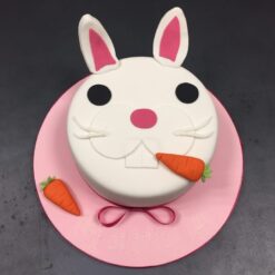 Artistic bunny cake decorated with fondant ears and colorful accents.