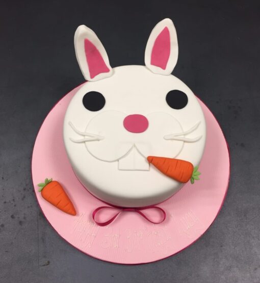 Artistic bunny cake decorated with fondant ears and colorful accents.