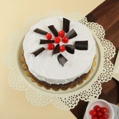Elegant cake with vanilla and Black Forest layers, topped with cherries and whipped cream.