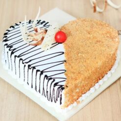 Delicious heart-shaped butterscotch cake with whipped cream and fresh cherries