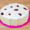 White Chocolate Cherry Cake topped with fresh cherries, white chocolate shavings, and creamy frosting on a white plate.
